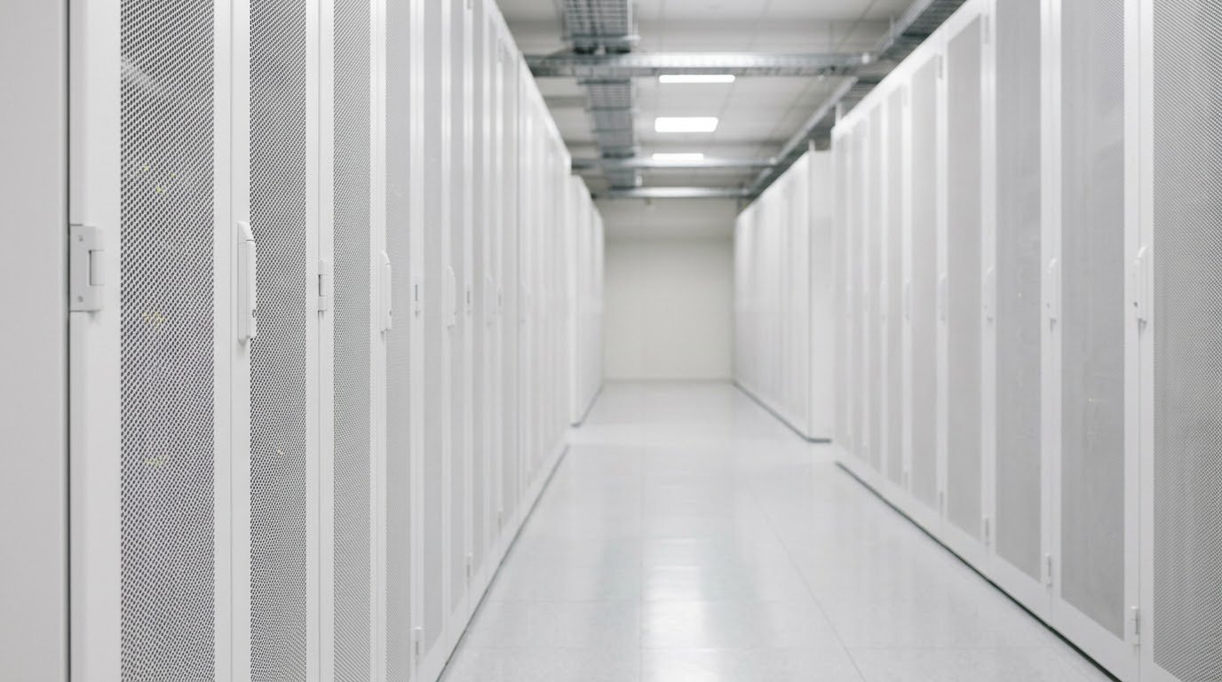 A data-centre aisle; over it, a record has its personal details redacted before labelling, and a lineage strip traces the dataset from raw to redacted, labelled and a versioned export.